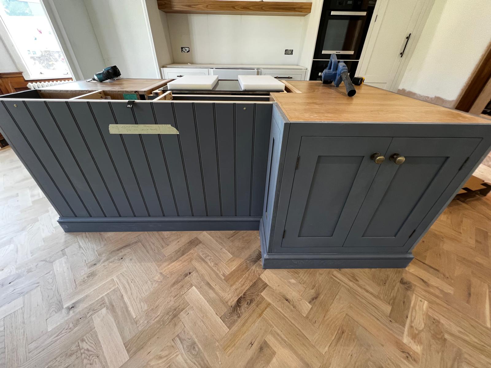 Hand-painted navy kitchen island with brass hardware, fitted over a herringbone oak floor